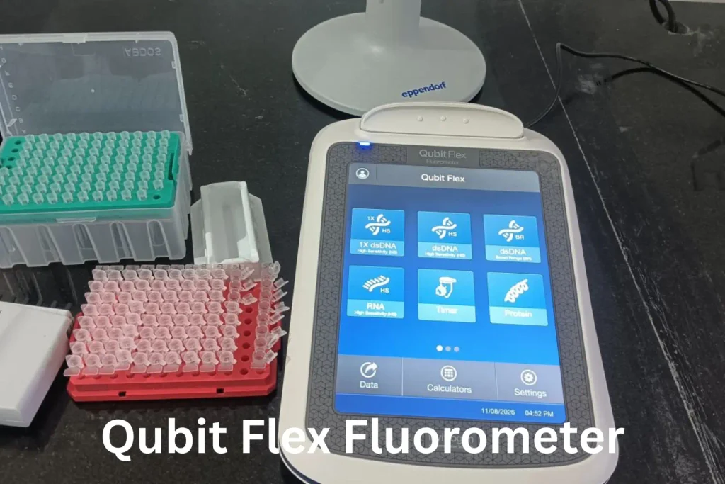 Qubit Flex Fluorometer on a laboratory bench displaying DNA and RNA quantification assay options, with microplate tubes and laboratory equipment nearby.
